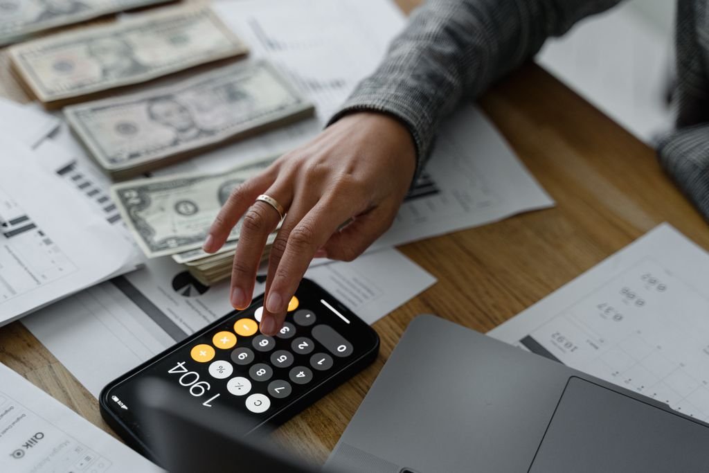 How to Budget Biweekly Paychecks: A Practical Step-by-Step Guide Hand using a calculator over financial charts