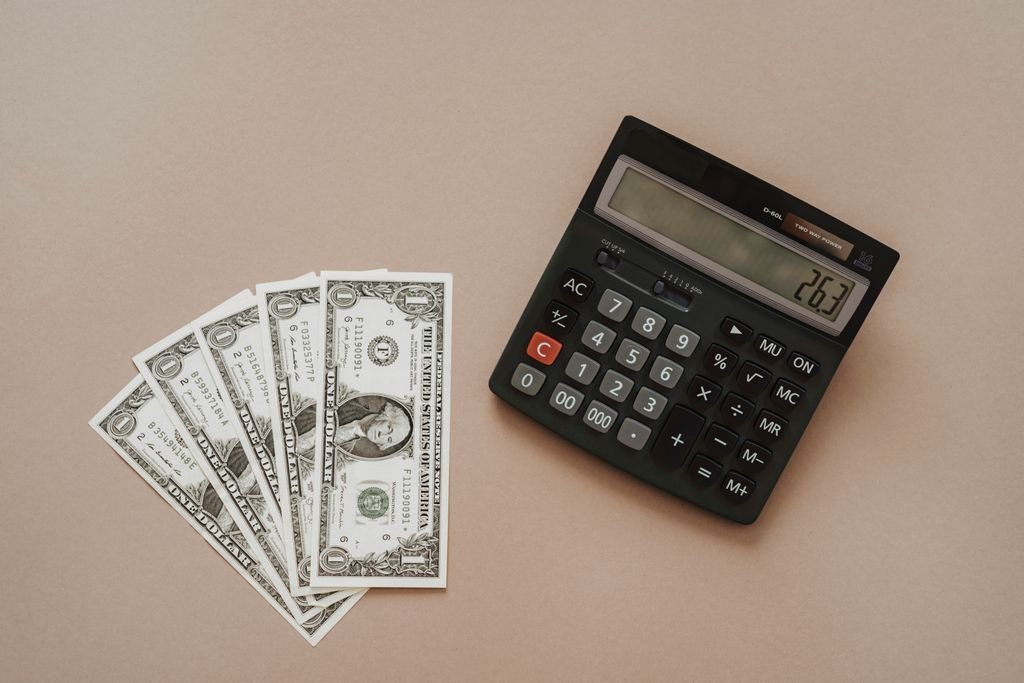 Debt Consolidation vs. Debt Settlement: Which Is Better? US banknotes beside a calculator
