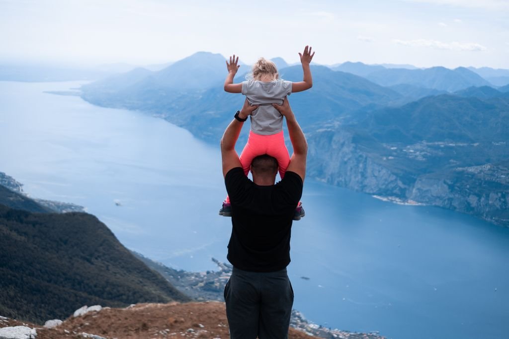 How Much Life Insurance Do I Need? A Practical Calculation Guide Adult carrying a child on their shoulders above a mountain lake