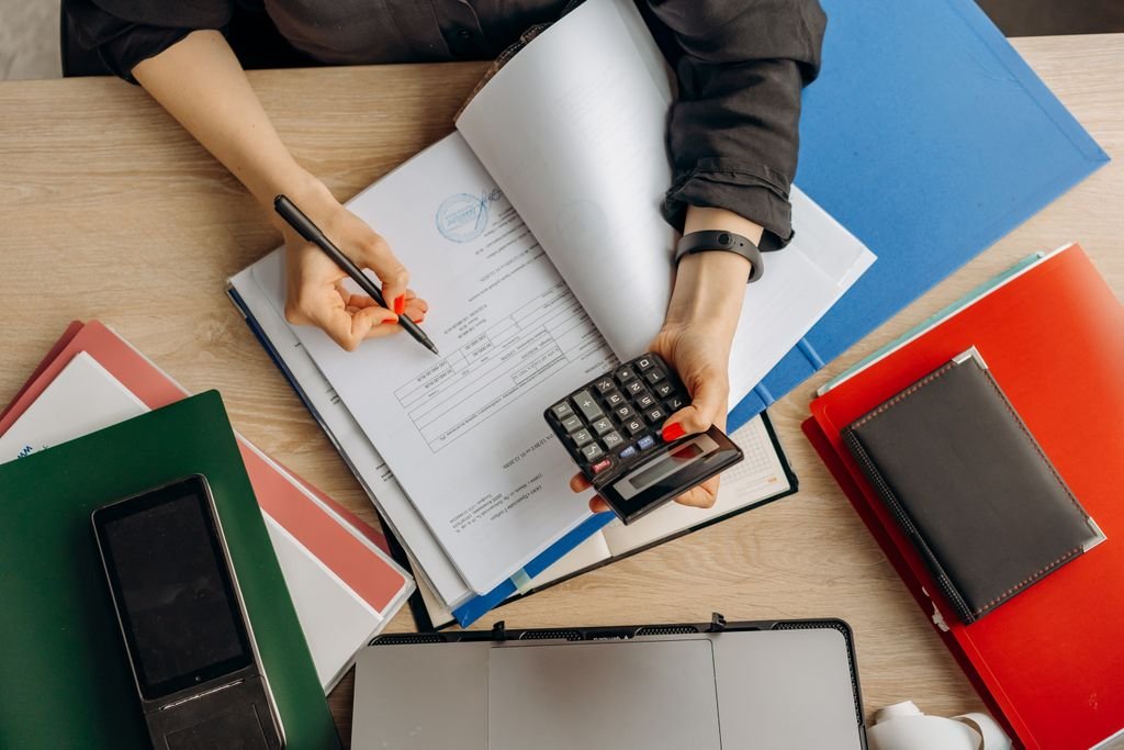 Net Income vs. Retained Earnings: Where a Company’s Profit Actually Goes Person reviewing paperwork with a calculator on a desk