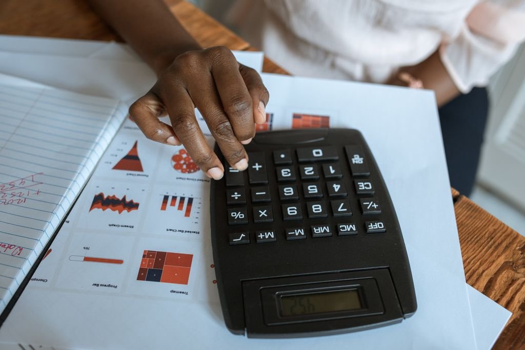 Gross Profit vs. EBITDA: What Each Metric Reveals About a Business Hand using a calculator beside financial charts