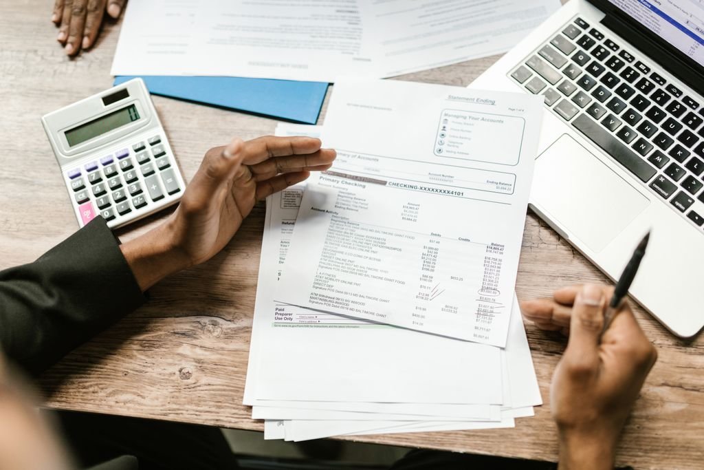 People reviewing bank paperwork with a calculator and laptop