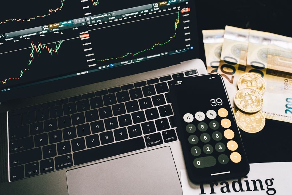 What Is a Wrap Account? Fees, Benefits, Risks and Examples Laptop showing trading charts beside a phone calculator