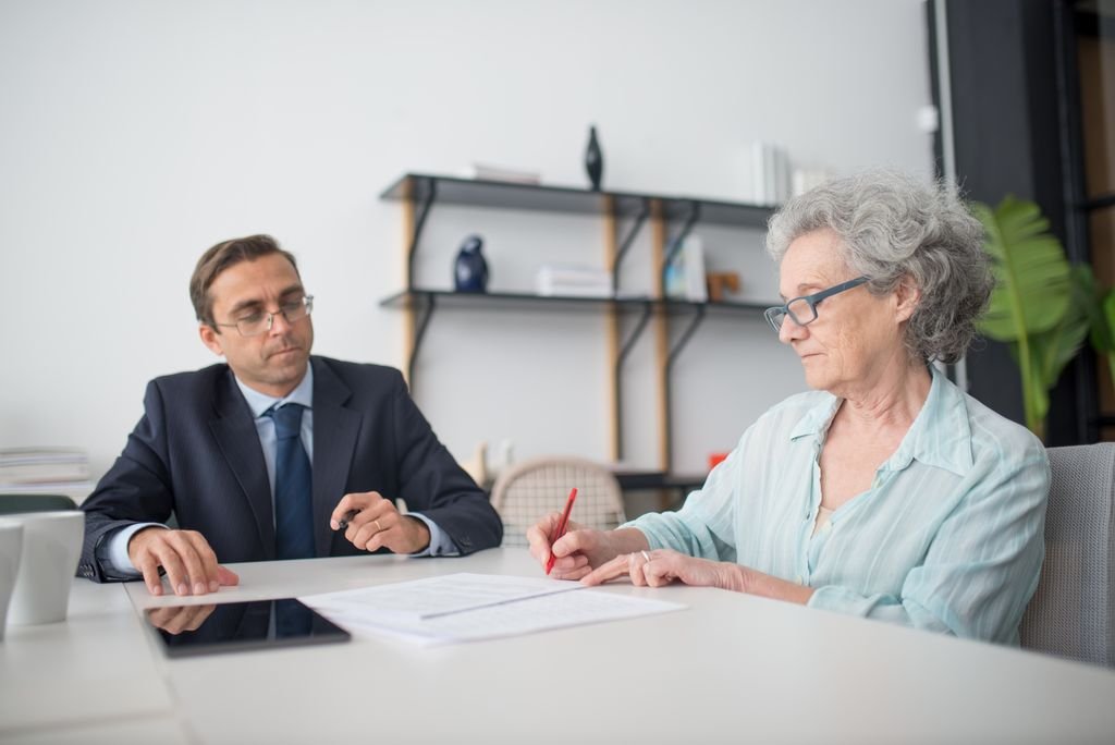 Older woman discussing documents with a man at a desk