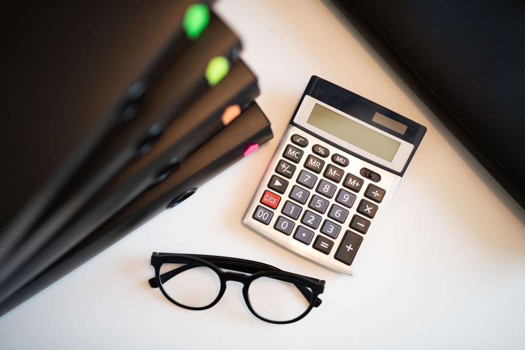 Estate Account: What It Is, How to Open One and Who Can Use It Calculator and eyeglasses beside document folders on a desk