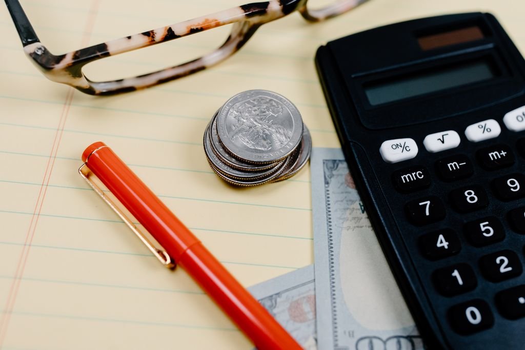 Calculator, coins and glasses on a notepad for retirement income planning
