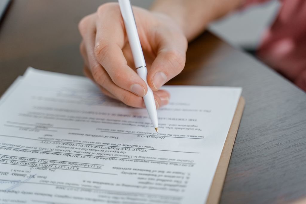 Close-up of a hand signing a document with a pen