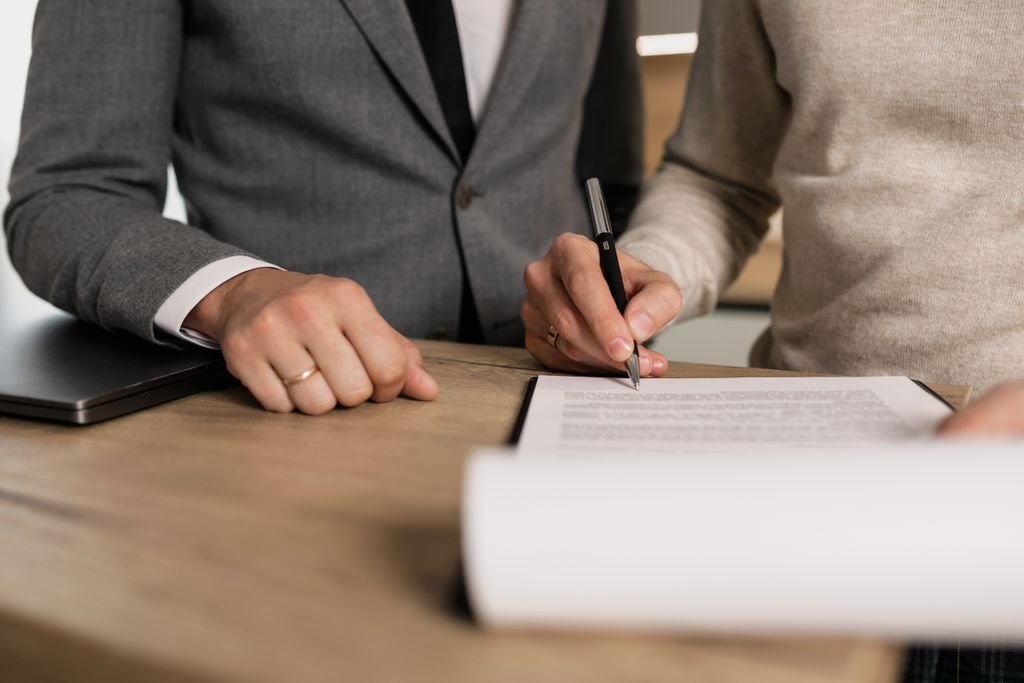 Disclaimer Trust: How It Works, Benefits and Important Rules Close-up of businessmen signing documents at a wooden table in an office.