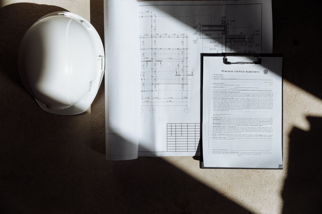 Hard hat, construction drawings and a clipboard
