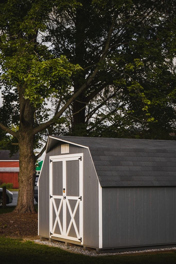 Other Structures Coverage: What Coverage B Protects and Its Limits Gray detached garden shed with white doors beneath backyard trees