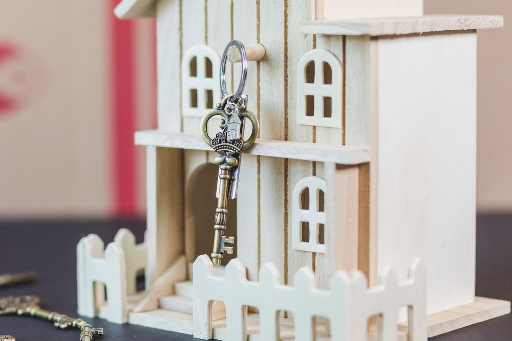 Transfer on Death Deed: How It Works, Benefits and State Rules White miniature house with an antique key hanging at the entrance