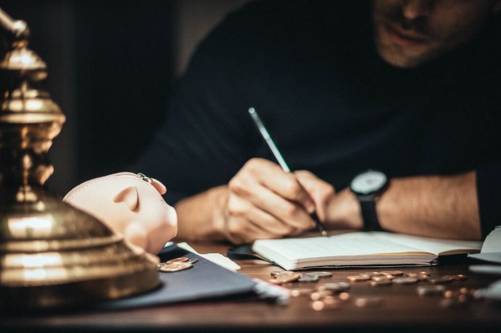 Does Opening a Savings Account Affect Credit Score? 5 Facts Man writing beside a piggy bank and scattered coins