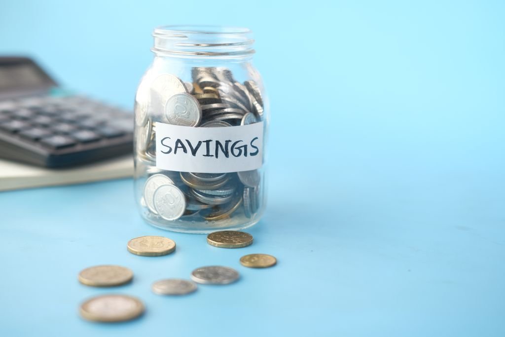 Reinvestment Risk: What It Is, Examples and Ways to Manage It Savings jar filled with coins beside a calculator