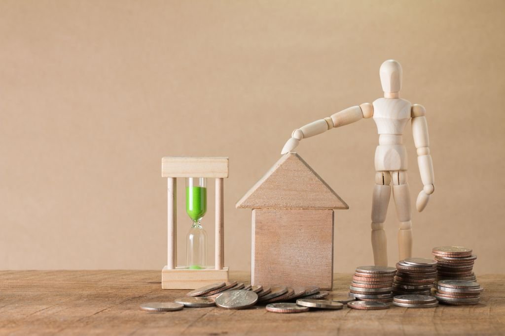 Inheritance Advance: How It Works, Costs and Risks Wooden figure beside a model house, stacked coins and an hourglass